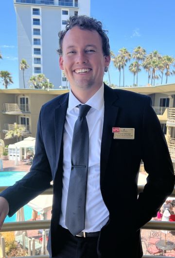 A Person In A Suit And Tie Standing On A Balcony